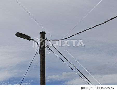 Wooden Utility Pole with Streetlight Under Overcast Sky Wooden Utility Pole with Streetlight Under Overcast Sky 144028973