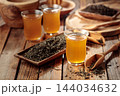 Freshly brewed green tea and dried tea leaves on an old wooden table. 144034632
