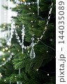 Close up of crystal garland decorations and warm lights on decorated green Christmas tree branches. 144035089