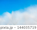 A fountain splashes and drops against a beautiful, bright, blue sky background 144035719