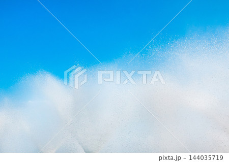 A fountain splashes and drops against a beautiful, bright, blue sky background 144035719