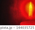 Red-orange burning candle flame close-up on dark black background 144035725