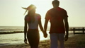 Romantic couple holding hands and walking on the beach at sunset 11407480