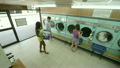 Three Young Adults do their laundry in the Launderette 13181147