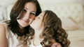 little girl kissing her mother on the bed 20880430