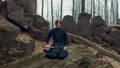 Concentrated man with a Japanese sword, a katana practicing Iaido in a pine forest. Wide angle. Back view. 61175996