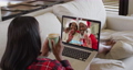 Mixed race woman on laptop video chat having coffee during christmas at home 72615299