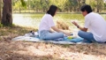 asian couple picnic together with happiness feeling at park with lake in springtime  73399387