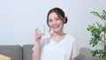 ソファに座って水を飲む笑顔の若い女性　 74456805