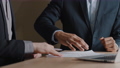 Unrecognizable Caucasian businessman and African-American man investor signing contract make handshake sitting at office desk. Close up male hands with paper documents shake hands signing agreement 75823449