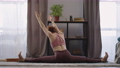 yoga workout of sporty flexible woman at home, lady is doing split and stretching hands, sitting on 76323250