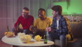 Three multiethnic guys enjoying friday evening together, watching tv and cheering with beer at home in neon lights 85877205