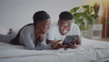 Happy memories. Young african american couple newlyweds resting in bed and watching photos on digital tablet in morning 85877221