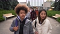 Close-up of two smiling multiracial friends, mixed race curly schoolboy and asian schoolgirl smiling and chatting while walking together with group of classmates through school park after study 86478154