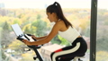 Exercise at home on spin bicycle fitness workout with screen. Woman training on stationary bike watching online video class for exercising cardio 86772167