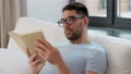 man in glasses reading book in bed at home 90808955