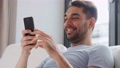 happy man with smartphone in bed at home 90808958