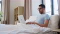 tired man in glasses with laptop working in bed 90808963
