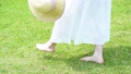 麦わら帽子を持って芝生を歩く女性の足元【パーツカット】 90955657