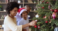 African couple and son decorating Christmas tree in living room 91079628