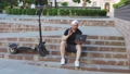 Man with laptop and modern electric kick scooter sitting at contemporary park. Ecological transportation concept 91476642