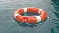 Orange lifebuoy ring floating on sea 93132351
