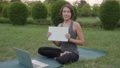Positive woman yoga trainer with white sheet in hands smiling, sitting outdoors. 93413297