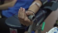 Close up view of woman donor donating her blood in a clinic, her hand squeezing an object and blood flowing via a tube. 93815788