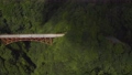 綺麗な山の谷に架かる真っ赤な橋を空撮 93875912