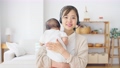 赤ちゃんを抱っこしながらビデオ通話で話す女性 94184626