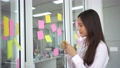 Young Creative businesswoman holding a marker and writing plan and share idea on glass wall with sticky note, Brainstorming and discussing and formulating, business strategies in tech startup office 94400636
