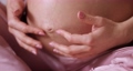 pregnant woman touching belly and sitting on the bed 95571342