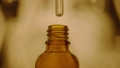 Drop of liquid, oil, medicine or extract dripping from a medical glass pipette in brown bottle. Serum dripping and forming air bubbles in a pipette on blurred yellow background. Concept of medicine. 96344548