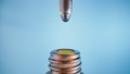Drop of brown liquid, oil, serum or tincture dripping from pipette in neck of a brown medical bottle. Macro shot of dripping drops of essential oil or iodine on blue background. Aroma, herbal extract. 96344554