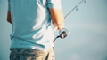 Unknown man fishing with spinning reel on the shore, close-up slow motion shot 96520485