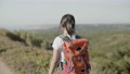 Girl carrying backpack, walking along the road in mountains. 96524535