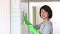 Japanese housewife cleaning the wall tiles, looking coldly at her unhelpful husband 96968142