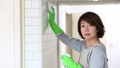 Japanese housewife cleaning the wall tiles, looking coldly at her unhelpful husband 96968143