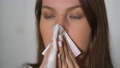 A young woman blows her nose into a paper handkerchief. Girl with runny nose. 98509835