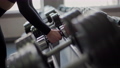 Female hands taking dumbbells for bodybuilding in the gym and then putting the dumbbells back. Close-up of woman taking and putting back weightlifting in sports club. 100176140