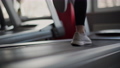 Close Up athlete's foot running on treadmill in fitness gym. Back view of white shoes having workout on treadmill. Low view sneakers training in sport club. 100176145