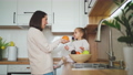 Beautiful mother and daughter spend time together in a white cozy kitchen. A mother shows her daughter different fruits. Mother's Day 100658706