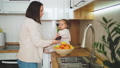 Beautiful mother and daughter spend time together in a white cozy kitchen. A mother shows her daughter different fruits. Mother's Day 100658713