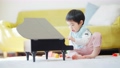一個 3 歲的男孩在客廳裡彈玩具鋼琴 100673450