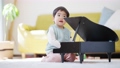 一個 3 歲的男孩在客廳裡彈玩具鋼琴 100673452